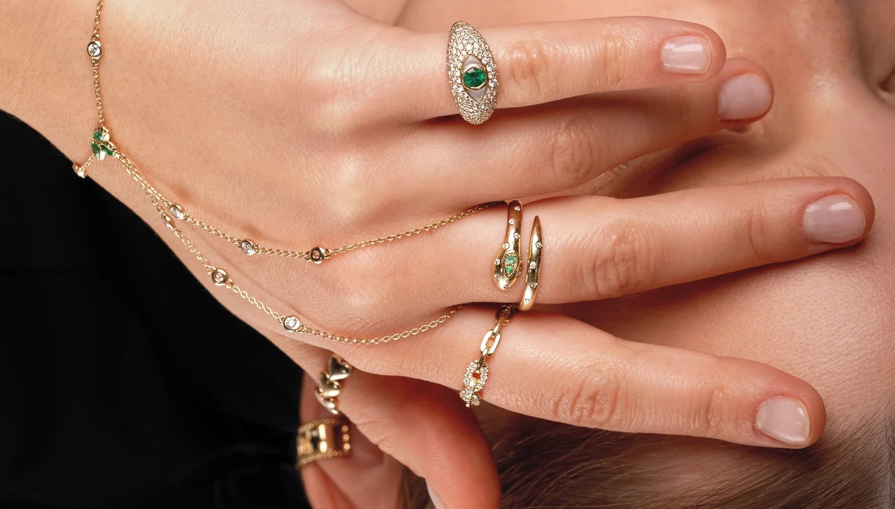 Sculptural gold rings, green stones and hand chains in close detail